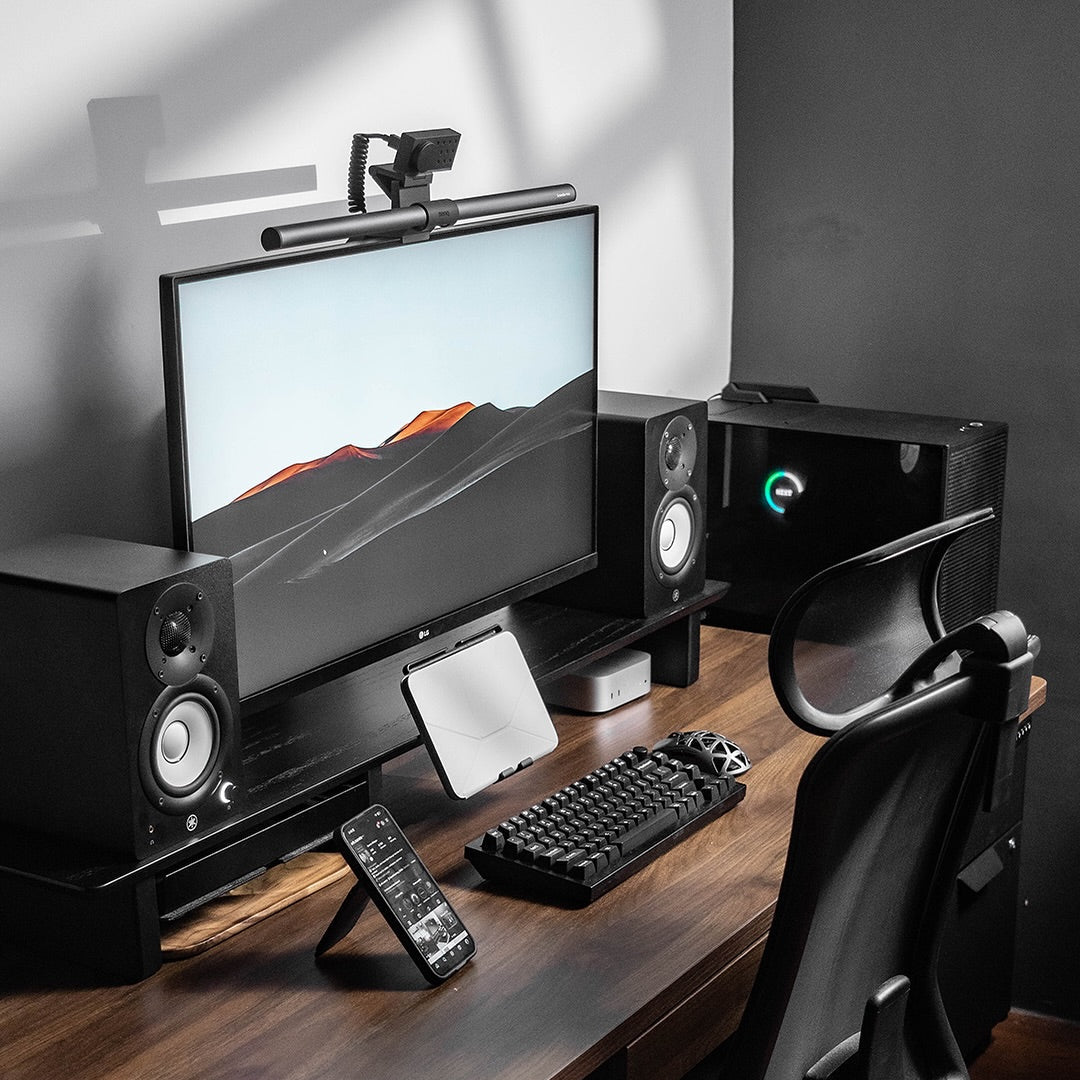 Modern home office setup with a computer monitor, keyboard, mouse, and speakers on a wooden desk.